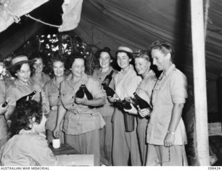 RABAUL, NEW BRITAIN. 1945-10-31. CORPORAL J. CALE ISSUING TWO BOTTLES OF BEER TO EACH OF THE AUSTRALIAN ARMY MEDICAL WOMEN'S SERVICE PERSONNEL OF 118 GENERAL HOSPITAL