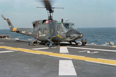 Flight deck crewmen remove tie-down chains from a UH-1N Iroquois helicopter aboard the amphibious assault ship USS GUAM (LPH 9)