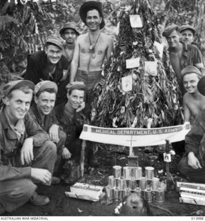BUNA, PAPUA, 1942-12-05. AMERICAN SOLDIERS AT AN ADVANCED DRESSING STATION WITH A HAND MADE CHRISTMAS TREE DECORATED WITH SURGICAL COTTON WOOL AND CIGARETTE CARTONS. (PHOTOGRAPHER: G. SILK)