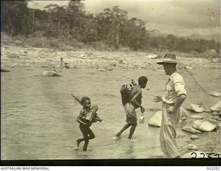 BOUGAINVILLE ISLAND, SOLOMON ISLANDS. C. 1945-02. 42933 CORPORAL R. TROTTER, COBDEN, VIC, WATCHES A NATIVE MOTHER AND HER CHILD FORD A SHALLOW RIVER NEAR A NATIVE VILLAGE IN THE TOROKINA AREA