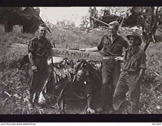 WAREGO, NEW GUINEA. 1943-12-09. A SAMPLE OF DIGGER HUMOUR. THE SIGN ON THIS JUNGLE DWELLING, GAZA HOUSE, BRINGS BACK MEMORIES OF PALESTINE. SHOWN ARE: VX43338 PRIVATE A. R. JOHNSTON OF PRAHRAN, VIC ..