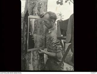 MILNE BAY, PAPUA. 1943-07-31. LEADING AIRCRAFTMAN H. DEVESON OF NORTH WILLIAMSTOWN, VIC, IS COPYING WITH A CAMERA THE SERIES OF PRINTS THAT MAKE UP THE AREA. THESE ARE SENT TO BOMBING SQUADRONS AS ..