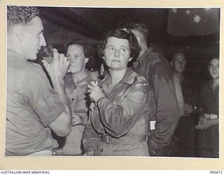 TOROKINA, BOUGAINVILLE. 1945-04-16. DRIVER E.J. O'SULLIVAN (1), AND SERGEANT M. BOYLE, AUSTRALIAN ARMY MEDICAL WOMEN'S SERVICE (2), COOLING OFF WITH SOFT DRINKS AT THE BUFFET COUNTER DURING A PAUSE ..