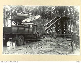 MILNE BAY, PAPUA, NEW GUINEA. 1944-03-31. MEMBERS OF THE 1ST FIELD SQUADRON, ROYAL AUSTRALIAN ENGINEERS, SLIDE A 6,000 GALLON DIESEL OIL TANK INTO POSITION ON A STAND, USING A POWER DRIVEN WINCH ..