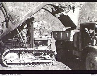 WAU-LABU ROAD, NEW GUINEA, 1946-01-09. A TD9 FRONT END LOADER LOADING RECOVERED GRAVEL INTO A TIPPER TRUCK FIFTY-EIGHT MILES FROM LABU. THE VEHICLES ARE OPERATED BY MEMBERS OF 8 MECHANICAL ..