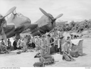 KIRIWINA, TROBRIAND ISLANDS, PAPUA. C. 1944-04. CHAPLAIN FLIGHT LIEUTENANT A. W. HARDIE OF BRISBANE, QLD, GIVING AIRMEN OF NO. 30 (BEAUFIGHTER) SQUADRON RAAF HOLY COMMUNION DURING AN EASTER SUNDAY ..