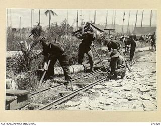 ALEXISHAFEN, NEW GUINEA. 1944-05. VX63721 PRIVATE B. KAYE, 2/15TH FIELD AMBULANCE (1), WITH MEMBERS OF HIS UNIT LAYING TROLLEY TRACKS. THE TRACKS ARE EXTENSIONS TO THE TRACK LAID AT THE CATHOLIC ..