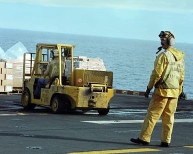 A flight deck crewman supervises a forklift operator aboard the amphibious assault ship USS GUAM (LPH 9), stationed off the coast of Beirut. The ship is providing support to US Marines deployed in Lebanon as part of a multi-national peacekeeping force following confrontation between Israeli forces and the Palestine Liberation Organization