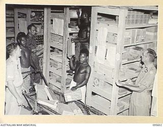 LAE AREA, NEW GUINEA. 1945-08-30. NATIVES UNDER THE SUPERVISION OF SERGEANT R. RENDALLS PREPARING ORDERS IN THE STATIONERY ISSUING SECTION, 9 LINES OF COMMUNICATION STATIONERY DEPOT. MAJOR G.F. ..