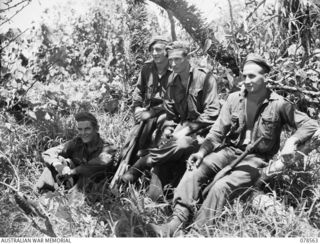 BOUGAINVILLE ISLAND, 1945-01-21. PERSONNEL OF THE 42ND INFANTRY BATTALION ENJOY A SPELL ON THEIR RETURN TO CAMP AFTER A PATROL THROUGH THE JUNGLE SWAMPS IN THE AREA. IDENTIFIED PERSONNEL ARE:- ..