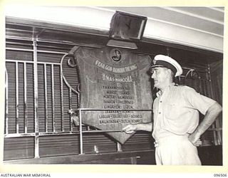 SIMPSON HARBOUR, RABAUL, NEW BRITAIN, 1945-09-10. COMMODORE (E) J. HANLON, ROYAL AUSTRALIAN NAVAL RESERVE, WHO HAS SERVED ABOARD HMAS MANOORA SINCE HER CONSTRUCTION ADMIRES THE SHIP'S HONOUR ROLL ..