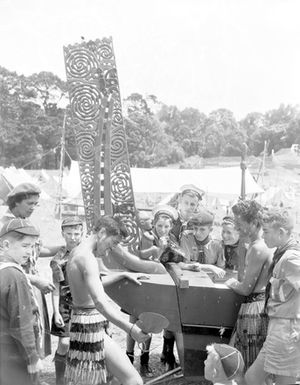 [Two Maori boys in piupiu posing beside imitation war canoe]