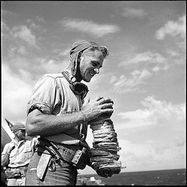 Crewmen loaded down with sandwiches on board USS Monterey (CVL-26); D-day on Saipan.