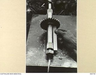 MADANG, NEW GUINEA. 1944-10-12. A DAMAGED TURRET OPERATING MAIN SHAFT BEING EXAMINED AT HQ 4 ARMOURED BRIGADE