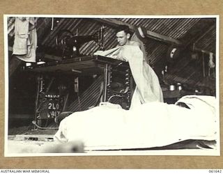 17 MILE, PORT MORESBY AREA, NEW GUINEA. 1943-12-13. QX19549 PRIVATE E. W. ALLAT OF THE RETURNED STORES DEPOT, 10TH AUSTRALIAN ADVANCED ORDNANCE DEPOT REPAIRING A DAMAGED TENT