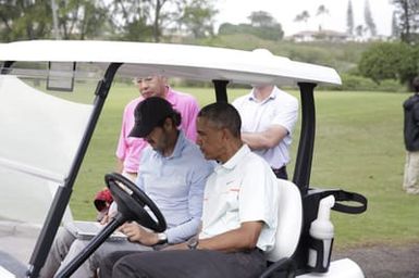 Barack Obama confers with Robert Baker after he plays golf in Kaneohe Bay, Hawaii, December 24, 2014