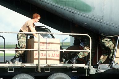 Members of the 8th Mobile Aerial Port Squadron load Christmas Drop containers onto a 374th Tactical Airlift Wing C-130 Hercules aircraft. The annual airdrop is a humanitarian effort providing aid to needy islanders throughout Micronesia during the holiday season