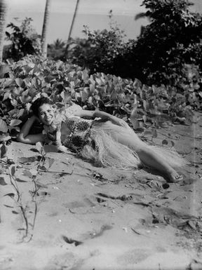 [Portrait of a Pacific island woman lying down on the shoreline]