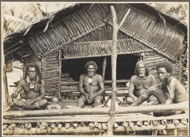 Scene in  Emo Village, [four men in front of a hut, Papua New Guinea] Frank Hurley