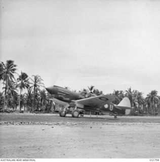 MOMOTE, LOS NEGROS ISLAND, ADMIRALTY ISLANDS. C. 1944-04. THE GREEN LIGHT FLASHES FROM THE CONTROL TOWER AND THE KITTYHAWK AIRCRAFT OF NO. 76 SQUADRON RAAF GATHERS SPEED ON THE RUN DOWN THE ..