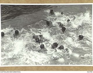 KUBA LAKE, RAMU VALLEY, NEW GUINEA. 1943-12-25. COMPETITORS IN THE "CORK SCRAMBLE" RACING OUT TO RETRIEVE CORKS AT THE CHRISTMAS CARNIVAL AND REGATTA ORGANISED BY MEMBERS OF THE 2/14TH INFANTRY ..