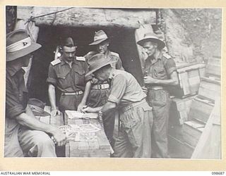 RABAUL, NEW BRITAIN. 1945-11-06. CAPTAIN R. WILLIAMS, HEADQUARTERS 11 DIVISION, MAKING AN ISSUE OF JAPANESE SWORDS TO A UNIT. SEVEN THOUSAND JAPANESE SWORDS WERE ISSUED TO TROOPS AT RABAUL AS ..