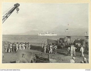 CAPE GLOUCESTER, NEW BRITAIN. 1944-10-15. TROOPS OF THE 2/31ST DOCKS OPERATING COMPANY UNLOADING UNITED STATES ARMY BARGES AT BORGEN BAY. THE DUTCH TROOPSHIP "SWEARTENHONDT" IS IN THE DISTANCE