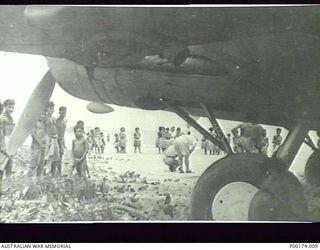 PORT MORESBY, NEW GUINEA. A "FLYING FORTRESS", NO. 12659 B17 BOMBER BOGGED IN SAND ON THE BEACH IS INSPECTED BY CURIOUS INHABITANTS