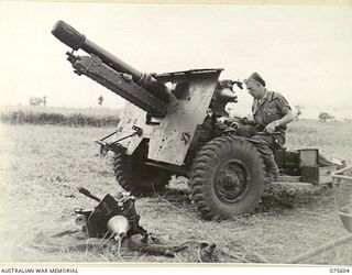 MARKHAM VALLEY, NEW GUINEA. 1944-08-28. VX83139 CORPORAL J.A. KERMONDE, ARTIFICER OF THE 214TH LIGHT AID DETACHMENT OVERHAULING THE SIGHTS OF A 25 POUNDER GUN OF THE 4TH FIELD REGIMENT