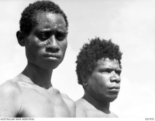 SALAMUA, NEW GUINEA. 1943-09-20. TWO NATIVE LABOURERS. THE ONE ON THE LEFT HAS BEEN IN JAPANESE HANDS AND THE ONE ON THE RIGHT HAS BEEN WORKING FOR THE AUSTRALIAN NEW GUINEA ADMINISTRATIVE UNIT. ..