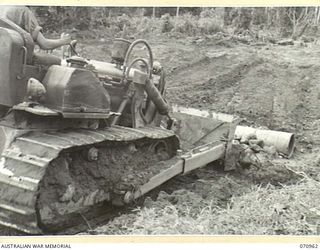 ZENAG, NEW GUINEA, 1944-02-27. A D6 ANGLE LDOZER FROM THE 2/9TH FIELD COMPANY, ROYAL AUSTRALIAN ENGINEERS FILLING OVER A DRUM CULVERT AT THE FIFTY EIGHT AND A HALF MILE POINT