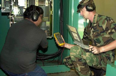 US Air Force (USAF) AIRMAN First Class (A1C) Jason Rice from the 15th Civil Engineer Squadron (CES), Hickam Air Force Base (AFB), Hawaii and Mr. William Cruz from the 36th CES, Andersen Air Force Base (AFB), Guam, check a generator at the Magellan Inn dining facility on Andersen AFB, after the damaging super-typhoon Pongsona hit the island