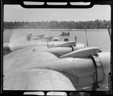 TEAL (Tasman Empire Airways Limited) Flying boat refuelling, Akaiami, Aitutaki, Cook Islands, showing men in boats with barrels of fuel