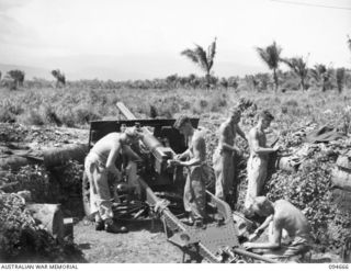 TOL AREA, NEW BRITAIN. 1945-08-02. GUNNERS OF 2/14 FIELD REGIMENT, ROYAL AUSTRALIAN ARMY, CLEANING A 25 POUNDER AFTER A SHELLING OPERATION ON JAPANESE POSITIONS IN THE HILLS. THIS IS NO. 1 GUN, 27 ..