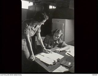 Lae, New Guinea. 1944-08-02. Sister K. P. Bonnin, Second in Charge (right) and Sister D. G. Francis, checking plans for the day's staff work at 2/7th Australian General Hospital