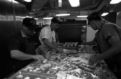 Navy and Marine mess management specialists aboard the amphibious assault ship USS SAIPAN (LHA 2) make cookies in preparation for the arrival of evacuees from the U.S. Embassy in Monrovia, Liberia. The SAIPAN is on station off the coast of Liberia FOR Operation Sharp Edge