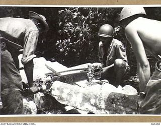 FINSCHHAFEN AREA, NEW GUINEA. 1943-11-09. COLOURED ENGINEERS OF THE 870TH UNITED STATES ENGINEER AVIATION BATTALION USING A POWER SAW TO CUT COCONUT PALM LOGS FOR THE DECKING OF THE NEW BRIDGE ..