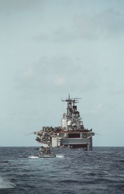 An LCM-8 mechanized landing craft approaches the amphibious assault ship USS SAIPAN (LHA 2) as the utility landing craft LCU-1643 backs out of the SAIPAN's well deck during Operation Sharp Edge. Marines embarked aboard the SAIPAN are being sent to the U.S. Embassy in Monrovia, Liberia, to augment security and evacuate U.S. and foreign nationals from the fighting between government and rebel forces