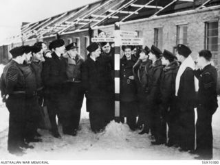 England. C. 1942-02. Members of No. 455 Squadron RAAF next to a signpost which was erected outside the hangar at RAF Station Swinderby by Nos. 300 and 301 Polish Squadrons. Left to right: Sergeant ..