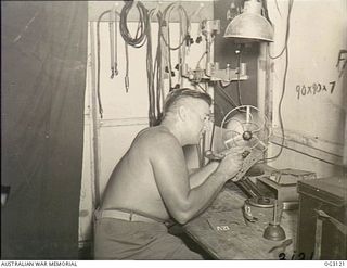 TOROKINA, BOUGAINVILLE ISLAND, SOLOMON ISLANDS. 1945-07-23. WARRANT OFFICER TED MCFARLAND OF CHELSEA, VIC, ADJUSTING AN AERIAL CAMERA IN PREPARATION FOR PHOTOGRAPHIC RECONNAISSANCE FLIGHT BY A ..