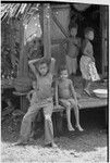 Children on veranda, taro plants and basket in background