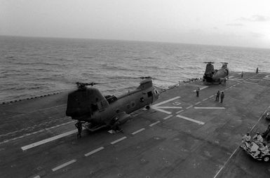 Two CH-46 Sea Knight helicopters parked aboard the amphibious assault ship USS GUAM (LPH 9) during Operation URGENT FURY