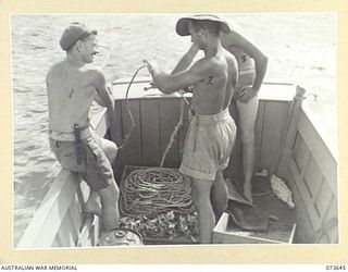 SALAMAUA, NEW GUINEA. 1944-06-02. MEMBERS OF THE 2ND MARINE FOOD SUPPLY PLATOON LAYING OUT A LONG LINE IN THE HARBOUR. THE LINE IS SET FOR ABOUT TWO HOURS BEFORE BEING LIFTED. IDENTIFIED PERSONNEL ..