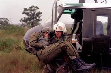 SPEC. 5 Harry Vercovic of the 68th Medical Detachment, 25th Infantry Division, removes CHIEF Warrant Officer Bill Kerr, a helicopter pilot with the 347th Aviation Co., from the simulated crash site of a UH-1 Iroquois helicopter. They are participating in an exercise on the east range of Schofield Barracks