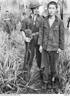 DUMPU, NEW GUINEA. 1943-10-05. SX12393 LANCE CORPORAL W. J. CULLEN OF THE 2/27TH INFANTRY BATTALION WITH A JAPANESE PRISONER, CAPTURED IN THE VALLEY