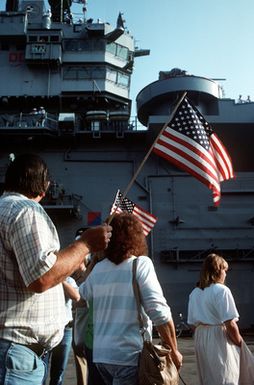 Family members and friends of crewmen aboard the amphibious assault ship USS GUAM (LPH-9) watch as the sailors depart for the Persian Gulf in support of Operation Desert Shield