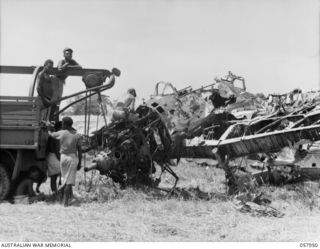 LAE, NEW GUINEA. 1943-10-04. UNITED STATES TROOPS AND NEW GUINEA NATIVES OBTAINING METAL FROM A CRASHED JAPANESE ZERO AIRCRAFT FOR SALVAGE