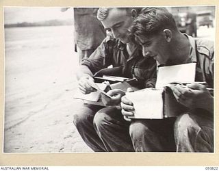 WEWAK AREA, NEW GUINEA, 1945-07-05. PRIVATE A.L. BEATTIE (1) AND PRIVATE S.L. ATTWELL (2), MEMBERS OF C COMPANY, 2/8 INFANTRY BATTALION, EXAMINING THEIR MID-YEAR HAMPERS AT THE UNIT REST CAMP ON ..