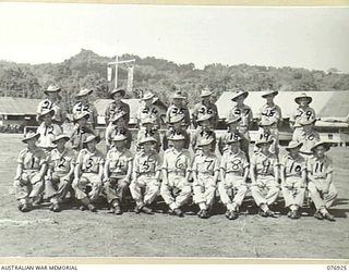 Group portrait of twenty nine personnel of the 18th Field Ambulance on the unit parade ground. Back row, left to right: Sergeant D F Yule; Lance Sergeant J Ruff; Corporal (Cpl) R S Goldstein; ..