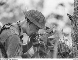 DONADABU AREA, NEW GUINEA. 1943-11-30. NX123472 LIEUTENANT G. H. LITCHFIELD, OFFICER COMMANDING, NO 7 PLATOON, 2/10TH AUSTRALIAN INFANTRY BATTALION GIVING ORDERS OVER HIS WALKIE TALKIE SET DURING ..